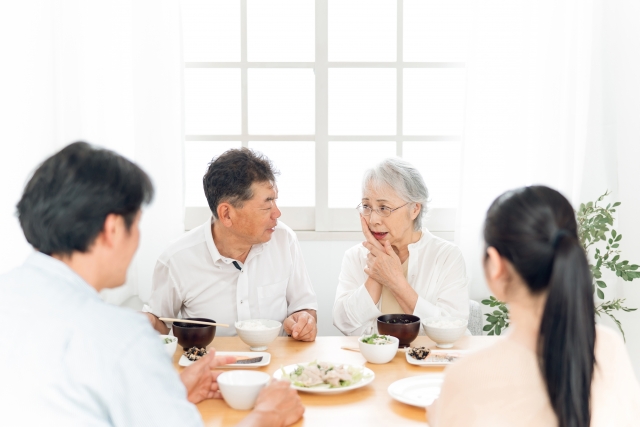 食卓で口元を押さえる高齢者女性